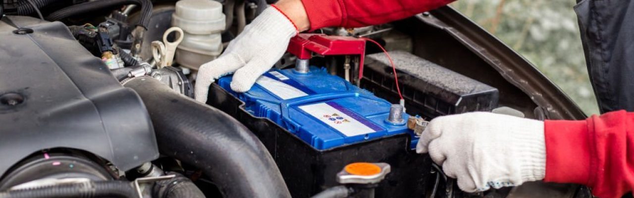a car mechanic installs a battery in a car. Battery replacement and repair. a car mechanic installs a battery in a car. Battery replacement and repair.